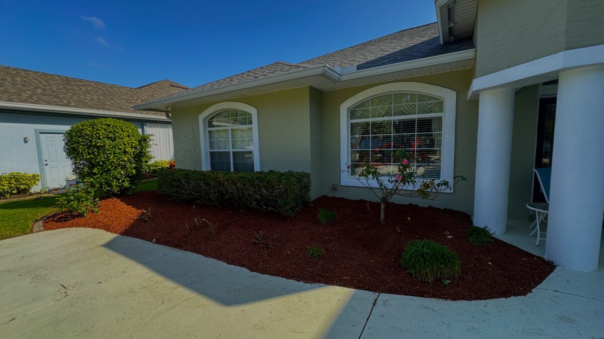 Fresh red mulch bed with shrubs along the front of a Palm Coast, FL home