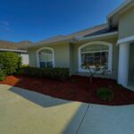 Fresh red mulch bed with shrubs along the front of a Palm Coast, FL home