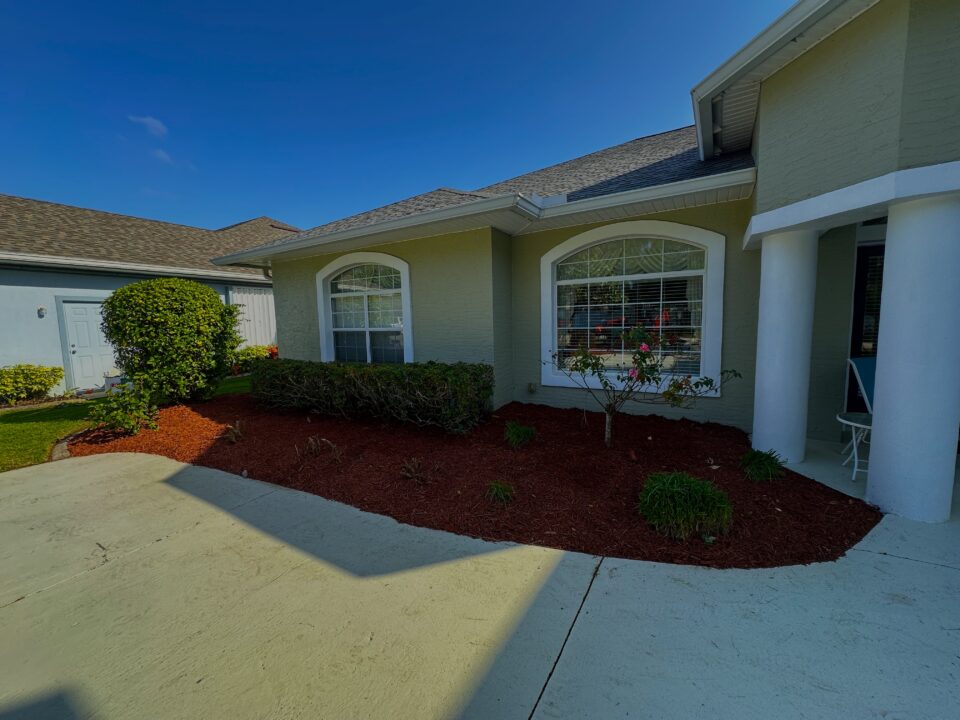 Fresh red mulch bed with shrubs along the front of a Palm Coast, FL home