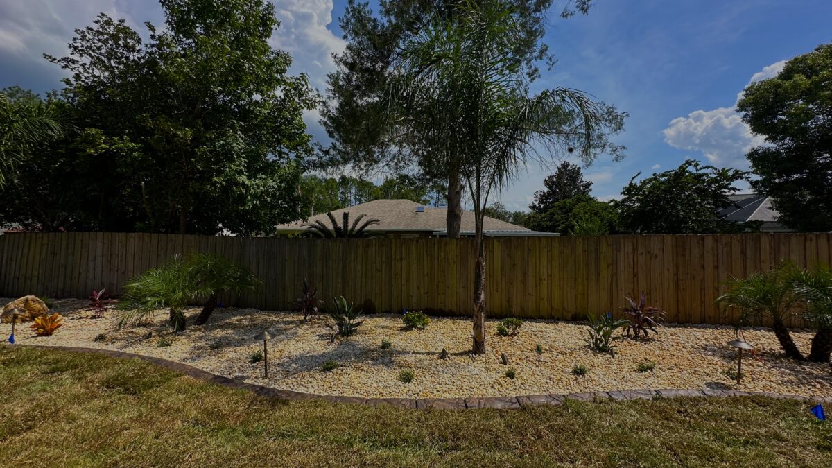 Newly planted backyard landscape bed with young shrubs and decorative rock at a Palm Coast, FL home