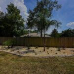 Newly planted backyard landscape bed with young shrubs and decorative rock at a Palm Coast, FL home